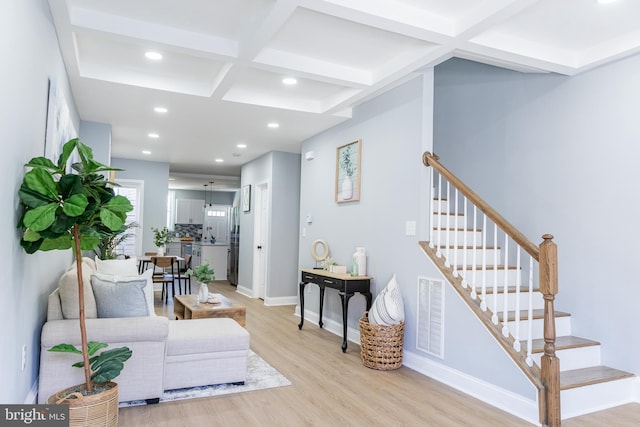 living area with coffered ceiling, light wood-type flooring, recessed lighting, beamed ceiling, and stairway
