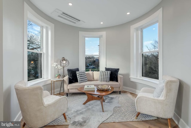 living area featuring baseboards, healthy amount of natural light, wood finished floors, and recessed lighting