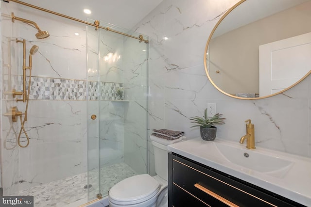 bathroom with tile walls, toilet, a marble finish shower, and vanity