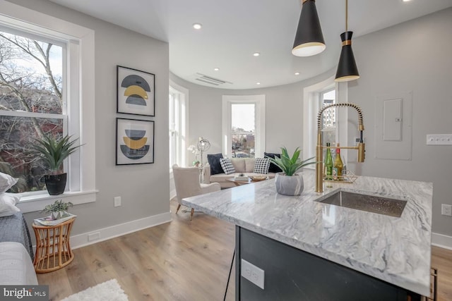 kitchen with open floor plan, light stone countertops, plenty of natural light, light wood-type flooring, and recessed lighting