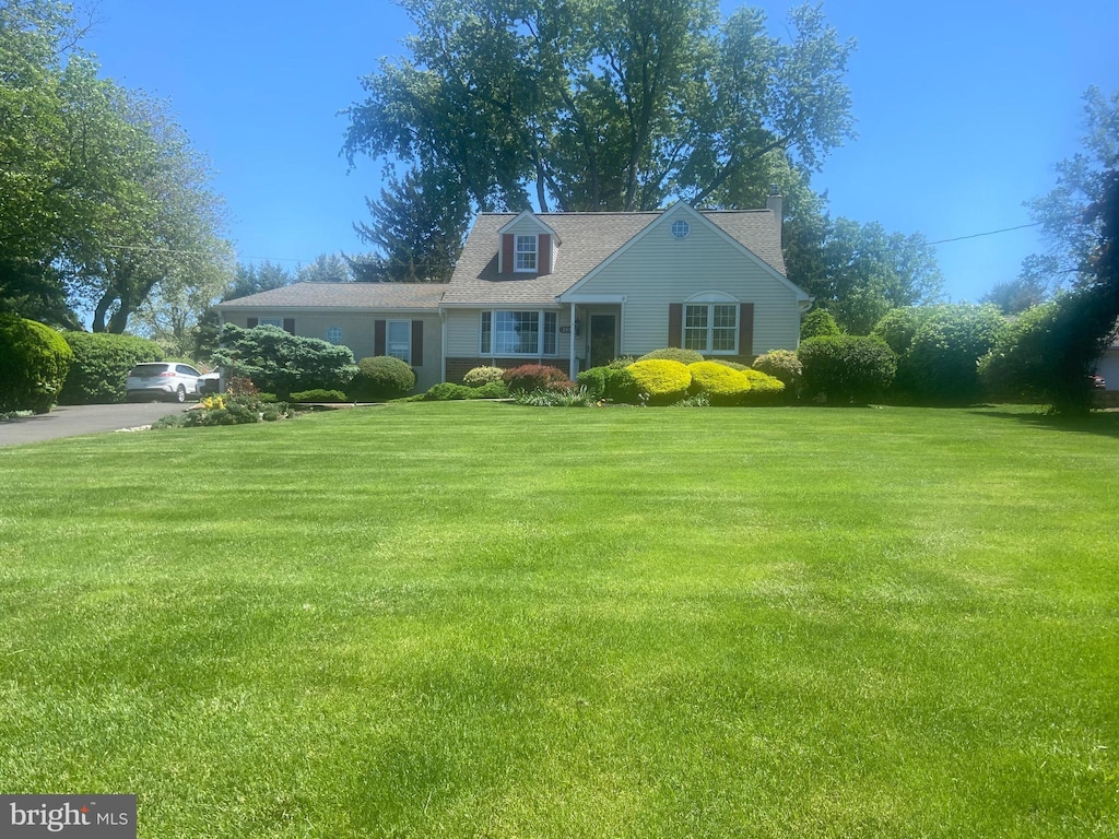 cape cod home featuring a front yard