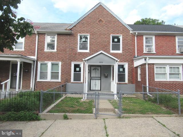 view of property with brick siding, a fenced front yard, and a gate