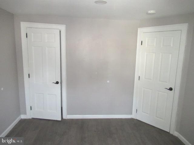 spare room featuring baseboards, dark wood-type flooring, and a smoke detector