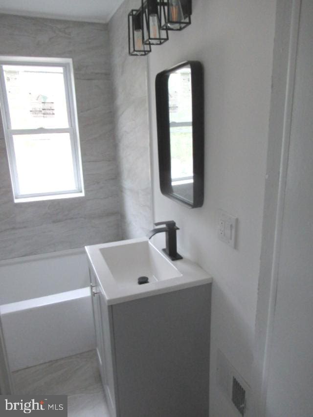 bathroom with healthy amount of natural light, vanity, and a bathtub