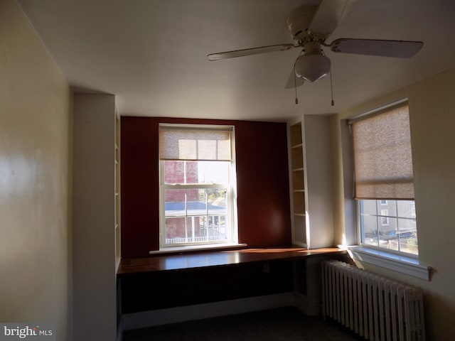 empty room with radiator, plenty of natural light, and a ceiling fan