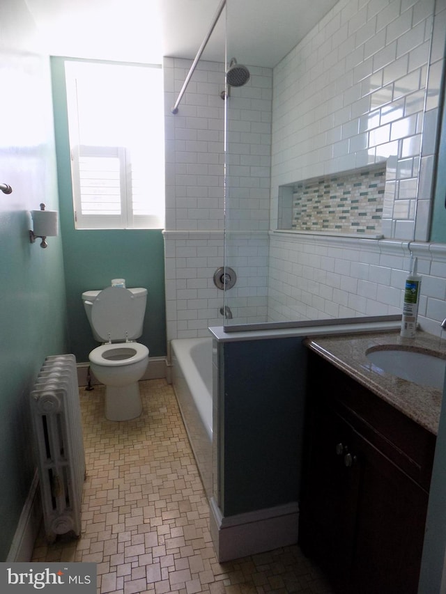 full bath with radiator, toilet, vanity, tub / shower combination, and tile walls