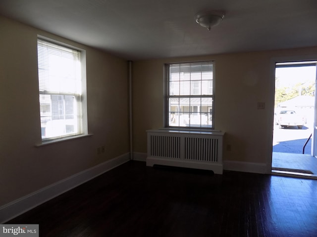 spare room with radiator heating unit, wood finished floors, plenty of natural light, and baseboards