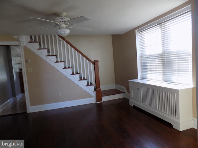 stairs with a ceiling fan, wood finished floors, baseboards, and radiator heating unit