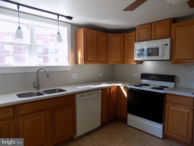 kitchen with white appliances, a sink, light tile patterned floors, light countertops, and brown cabinets