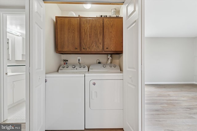 laundry area with cabinet space, washer and dryer, light wood finished floors, and baseboards