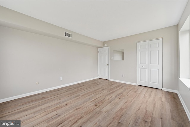 unfurnished bedroom with light wood finished floors, baseboards, and a closet