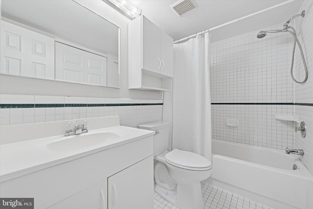 full bathroom with toilet, shower / tub combo with curtain, tile patterned floors, vanity, and tile walls