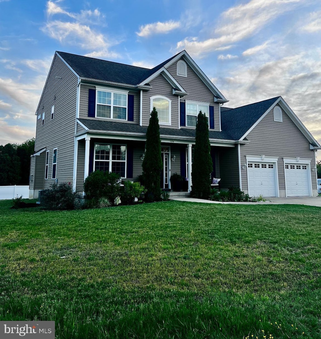 traditional-style house featuring a front yard, a garage, driveway, and a porch
