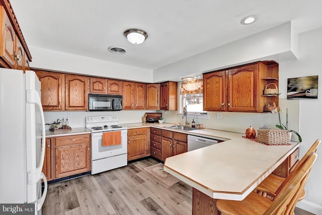 913 Pine Grove Rd, Fredericksburg, PA 17026 - kitchen with white appliances, a sink, a peninsula, brown cabinetry, and light wood-type flooring