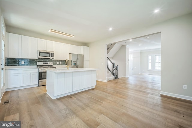5561 Jowett Ct, Alexandria, VA 22315 - kitchen featuring appliances with stainless steel finishes, decorative backsplash, light countertops, an island with sink, and white cabinetry