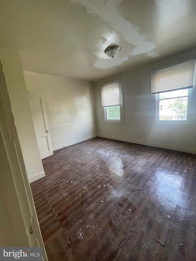 empty room featuring baseboards and dark wood-style flooring