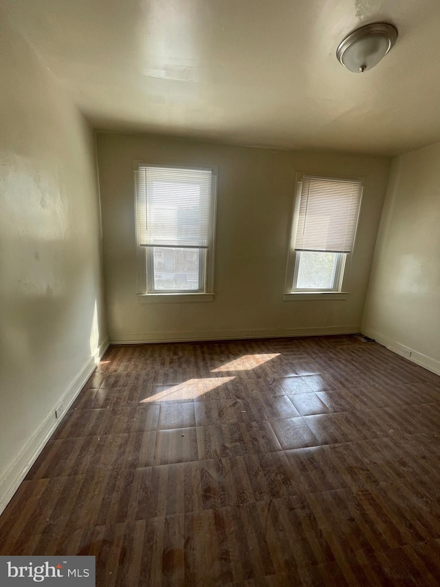 spare room featuring dark wood-style flooring and baseboards