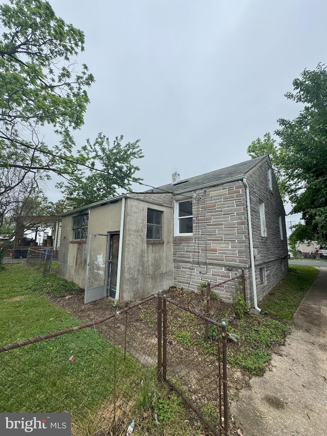 view of side of home featuring stone siding and fence