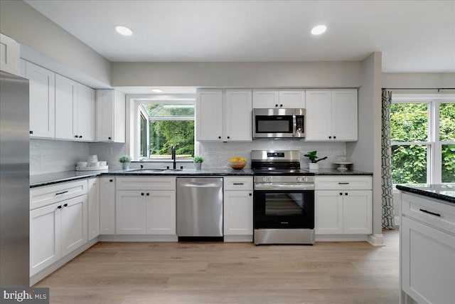 kitchen featuring appliances with stainless steel finishes, a sink, white cabinetry, tasteful backsplash, and recessed lighting
