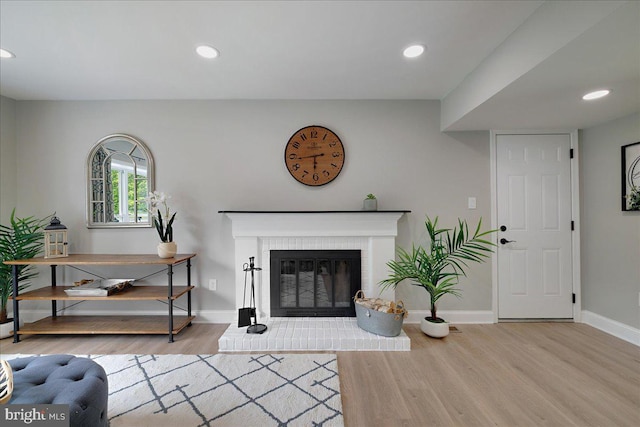 living area featuring wood finished floors, baseboards, a brick fireplace, and recessed lighting