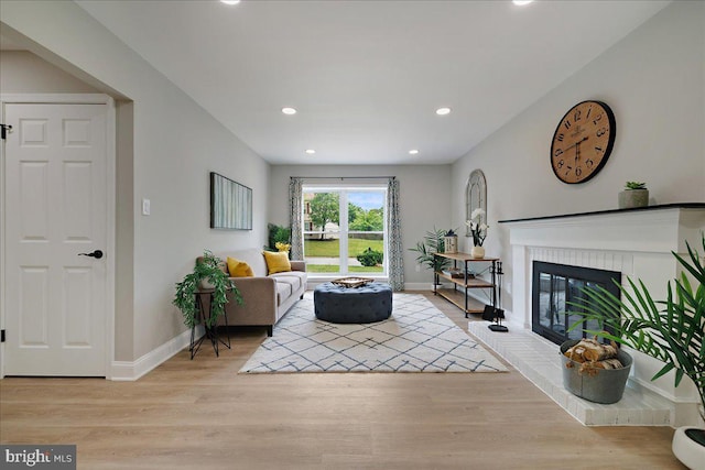 living room with recessed lighting, light wood finished floors, baseboards, and a brick fireplace