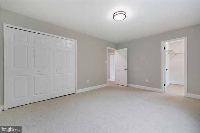 unfurnished bedroom featuring a closet, light carpet, and baseboards