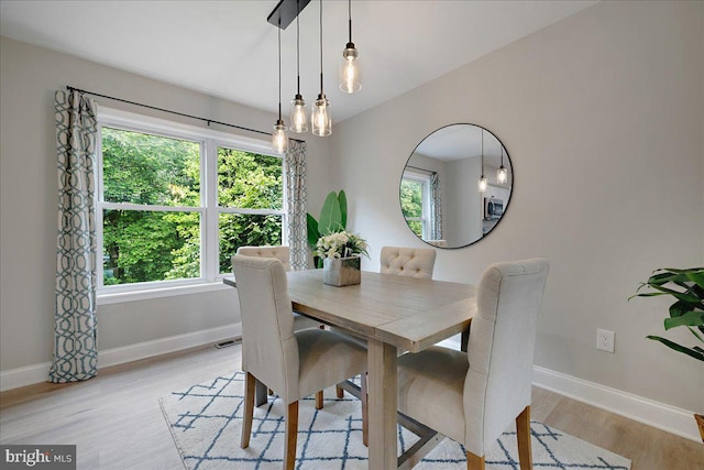 dining space featuring baseboards and light wood-type flooring