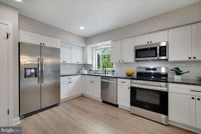 kitchen featuring appliances with stainless steel finishes, white cabinetry, light wood-style flooring, a sink, and recessed lighting