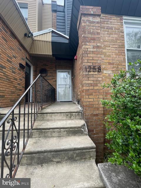 doorway to property featuring brick siding