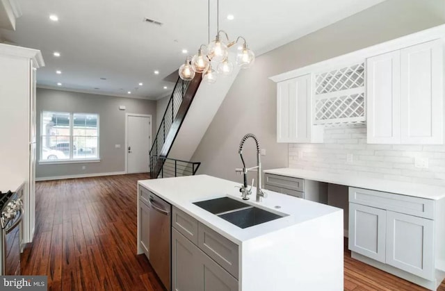 kitchen featuring appliances with stainless steel finishes, a sink, open floor plan, dark wood-type flooring, and decorative backsplash