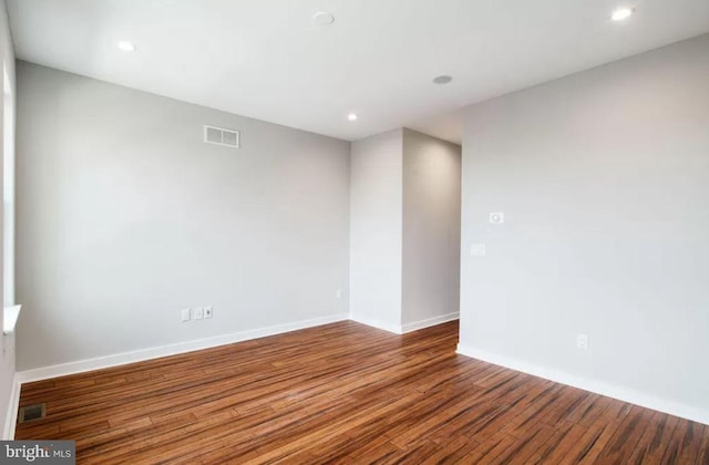 empty room featuring wood finished floors, baseboards, and recessed lighting