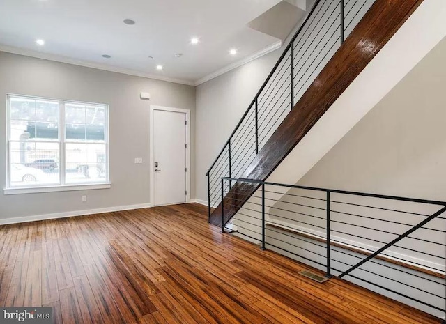foyer with wood-type flooring, ornamental molding, baseboards, stairway, and recessed lighting