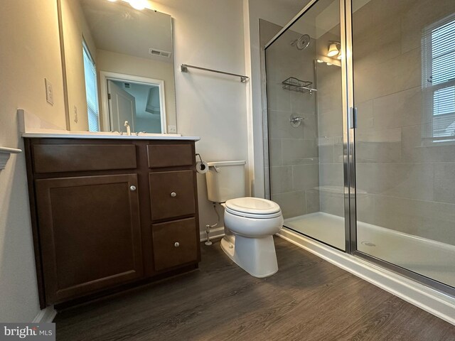 full bath featuring wood finished floors, a stall shower, toilet, and vanity