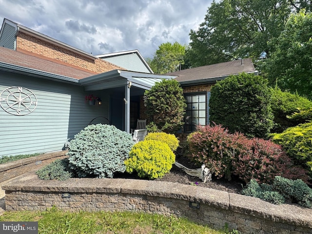 view of home's exterior featuring a shingled roof and brick siding