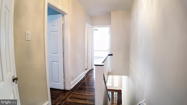 corridor with an upstairs landing, dark wood finished floors, and baseboards