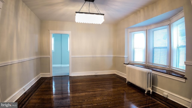 unfurnished room featuring radiator heating unit, dark wood-style floors, and baseboards