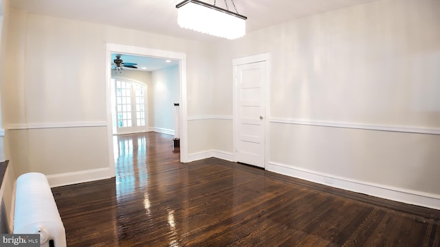 unfurnished dining area with dark wood-style flooring, ceiling fan, and baseboards