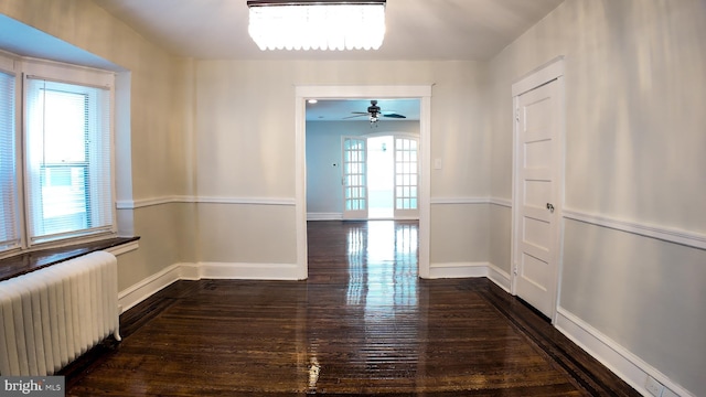 hallway with radiator, wood finished floors, and baseboards