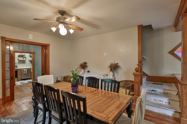 dining room with wood-type flooring, a ceiling fan, and stairs