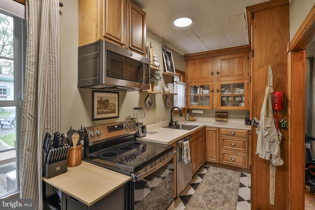 kitchen with appliances with stainless steel finishes, a sink, and brown cabinets