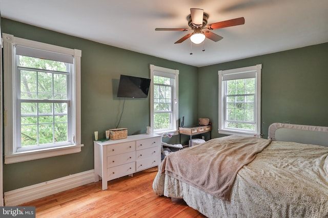 bedroom with light wood-type flooring, baseboards, and a ceiling fan