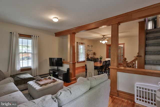 living room with decorative columns, wood finished floors, ceiling fan, and a baseboard radiator