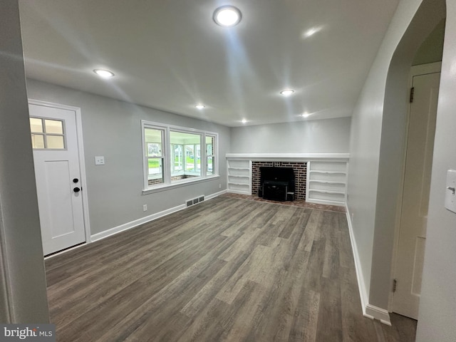3333 Stone Ridge Rd, York, PA 17402 - unfurnished living room featuring baseboards, dark wood-type flooring, arched walkways, a fireplace with flush hearth, and recessed lighting