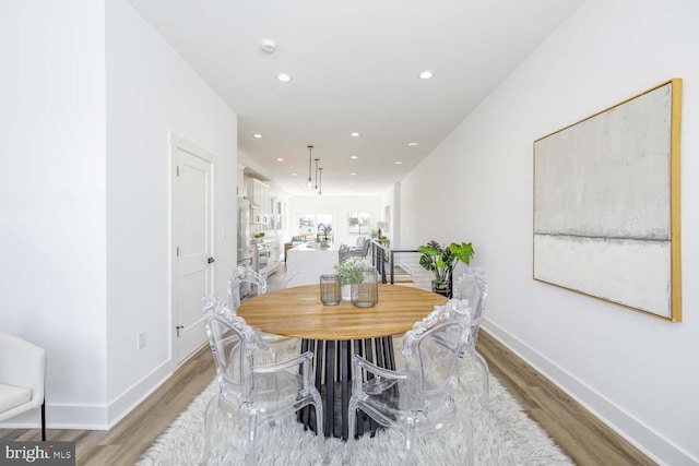 dining area featuring light wood finished floors, baseboards, and recessed lighting