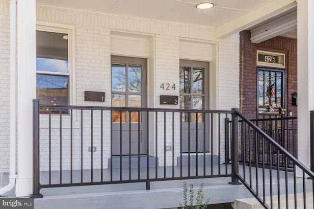 entrance to property featuring brick siding and covered porch
