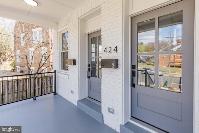view of exterior entry with brick siding and a porch