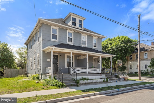 american foursquare style home with covered porch, fence, and roof with shingles