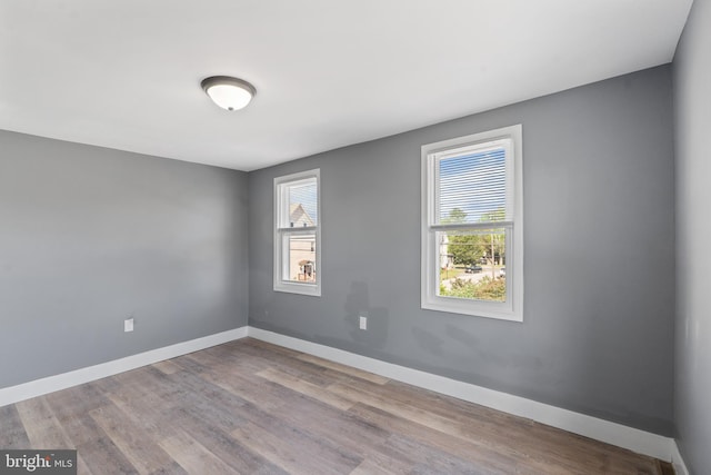 spare room with baseboards and wood finished floors
