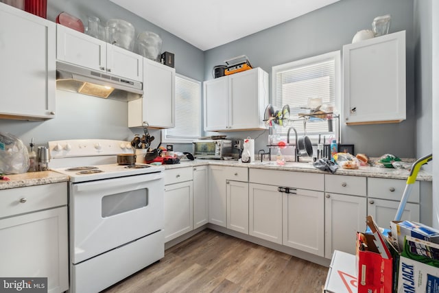 kitchen featuring under cabinet range hood, white electric stove, a sink, light wood finished floors, and white cabinetry