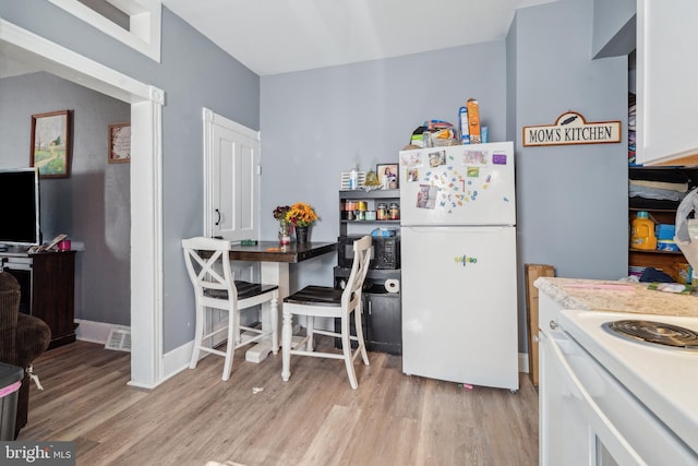 kitchen with white appliances, light wood-style floors, and white cabinetry